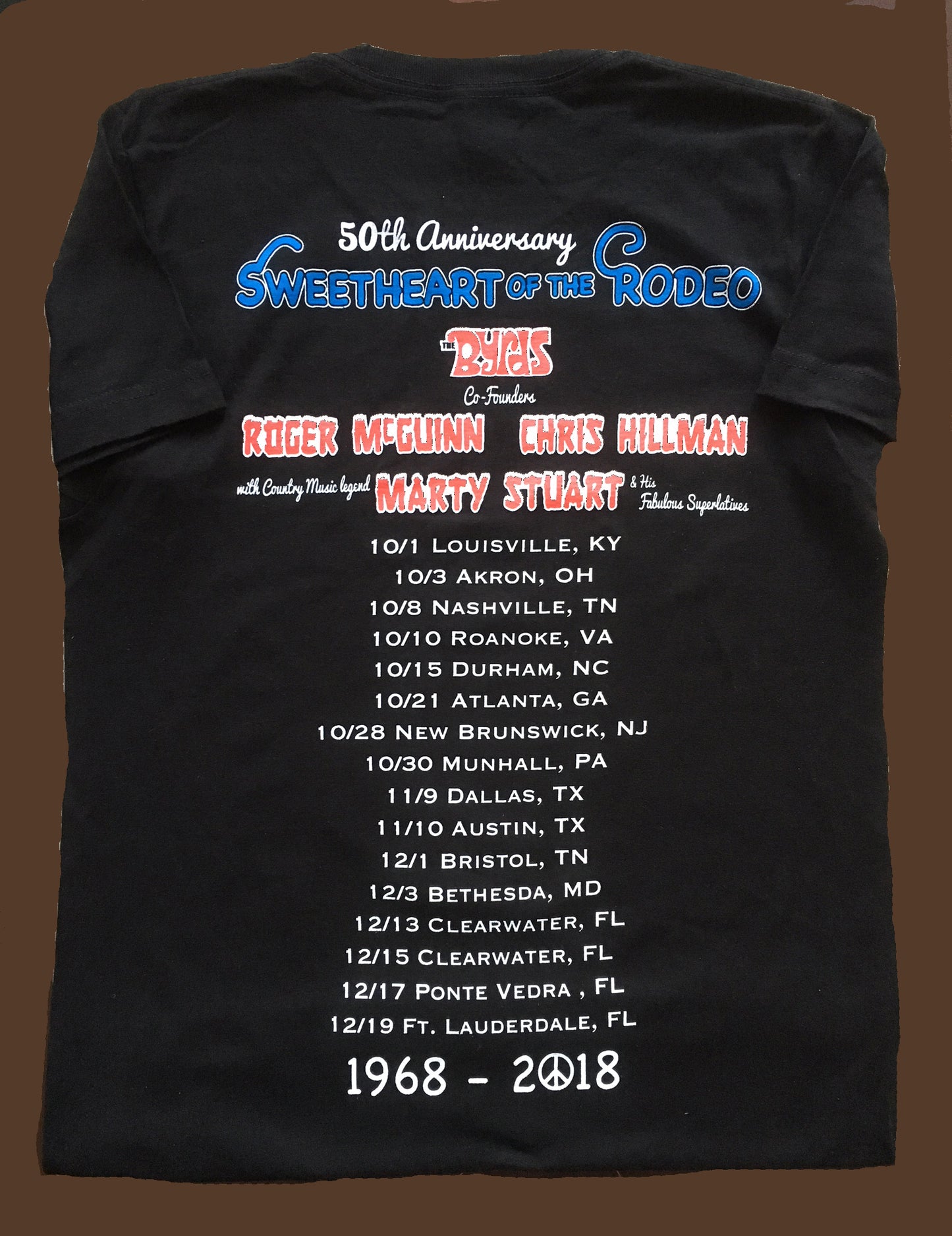 Black t-shirt with '50th Anniversary Sweetheart of the Rodeo' text and event details on a brown background
